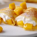 Mango pancakes filled with whipped cream and fresh mango, dusted with powdered sugar